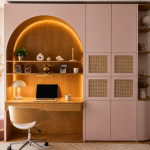 photo d'un bureau rose poudré et beige avec une alcôve arrondie, des étagères et des placards intégrés
