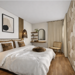 photo d'une chambre dans les tons beige et marron clair avec un lit dans les mêmes couleurs , des luminaires en rotin et un pan de mur décoré avec une tapisserie ornée de feuilles de ginko biloba, de couleur beige