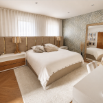 photo d'une chambre comprenant une tête de lit qui fait toute la largeur de la pièce, un grand tapis blanc et une tapisserie dans les tons vert