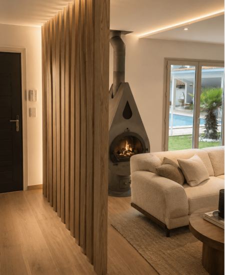 Entrée de maison chaleureuse avec tasseaux de bois, poêle design et canapé beigne